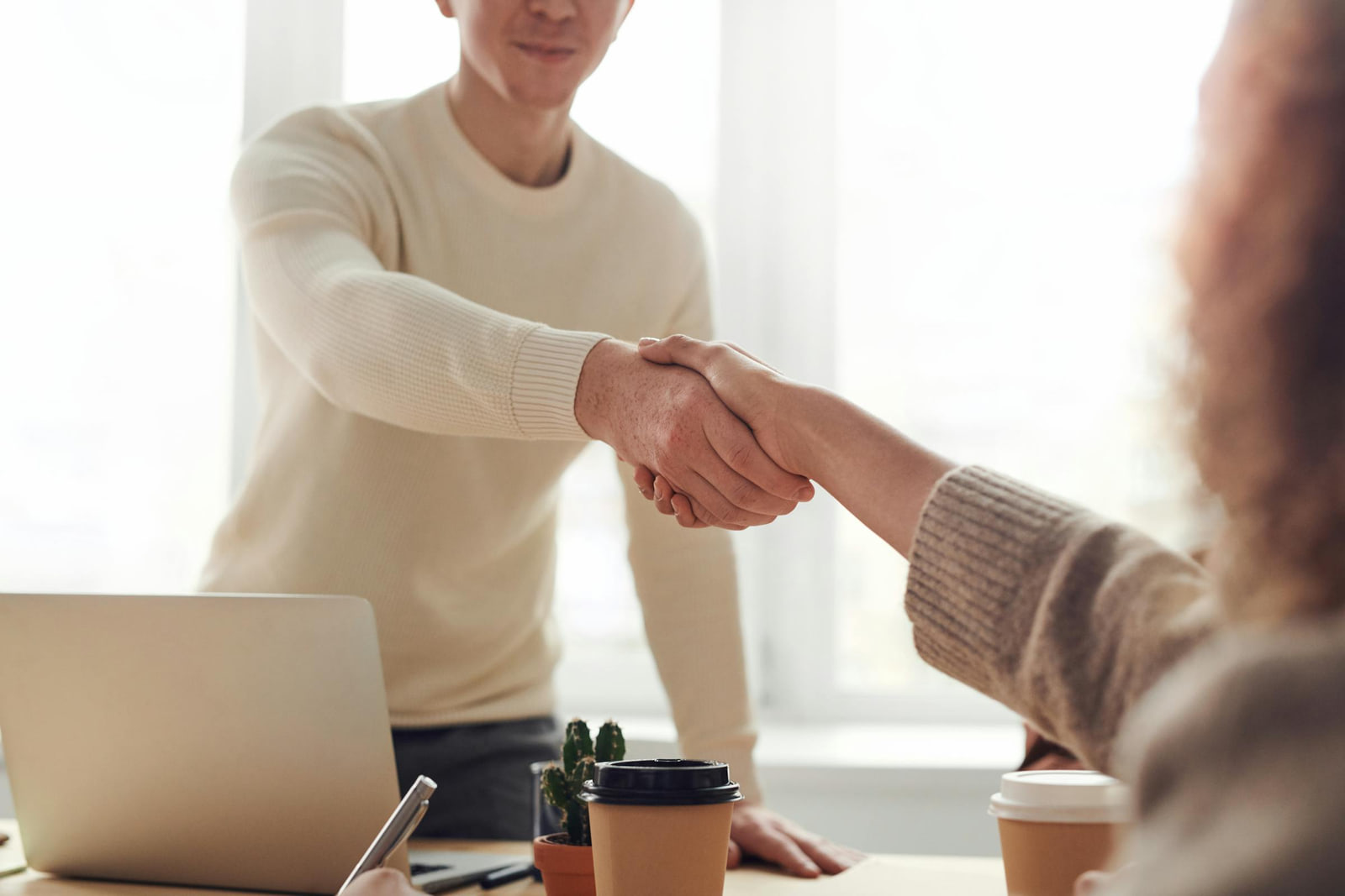 A recruiter and a candidate shaking hands across a desk